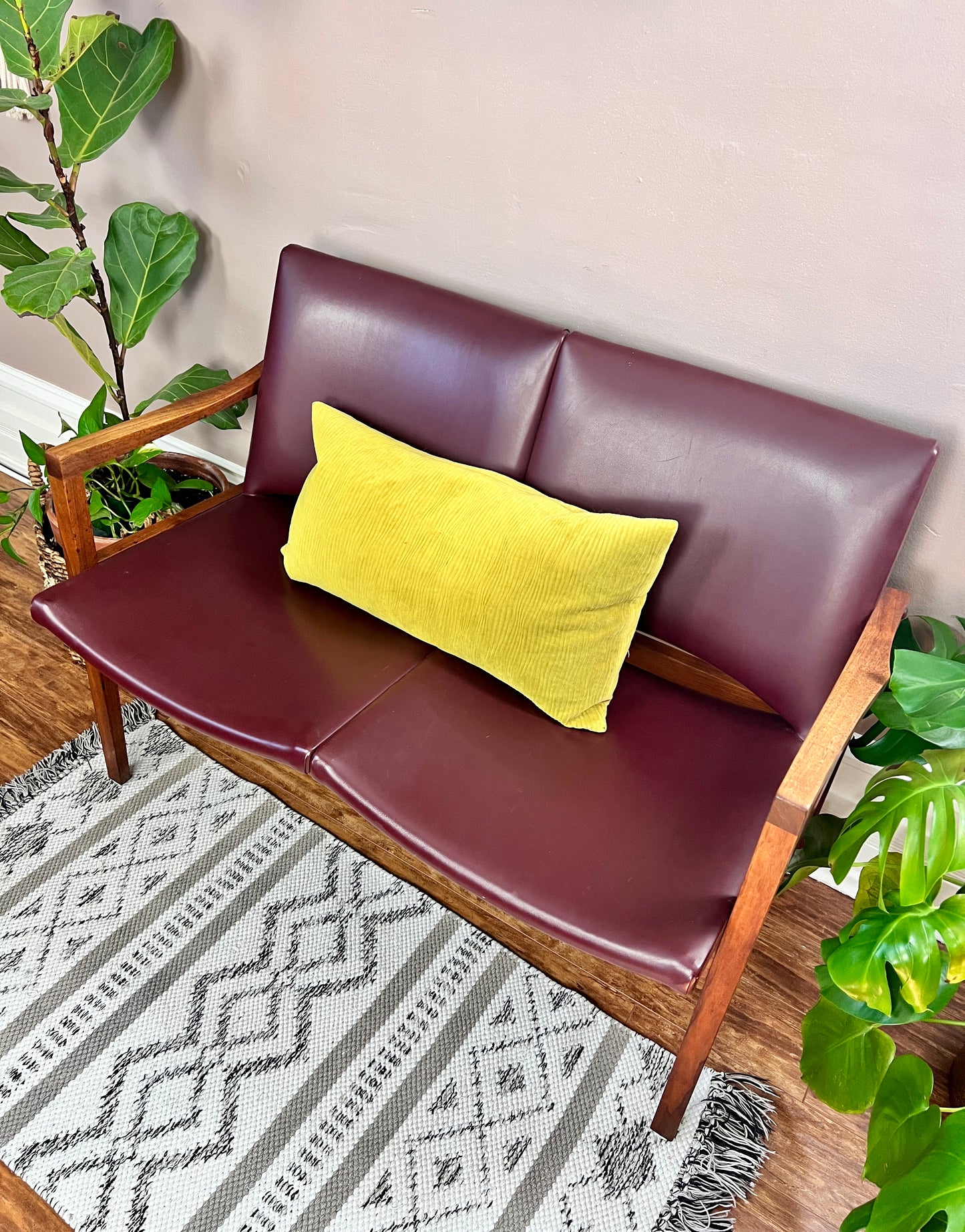 This is a vintage walnut 60s loveseat bench with burgundy vinyl upholstery.