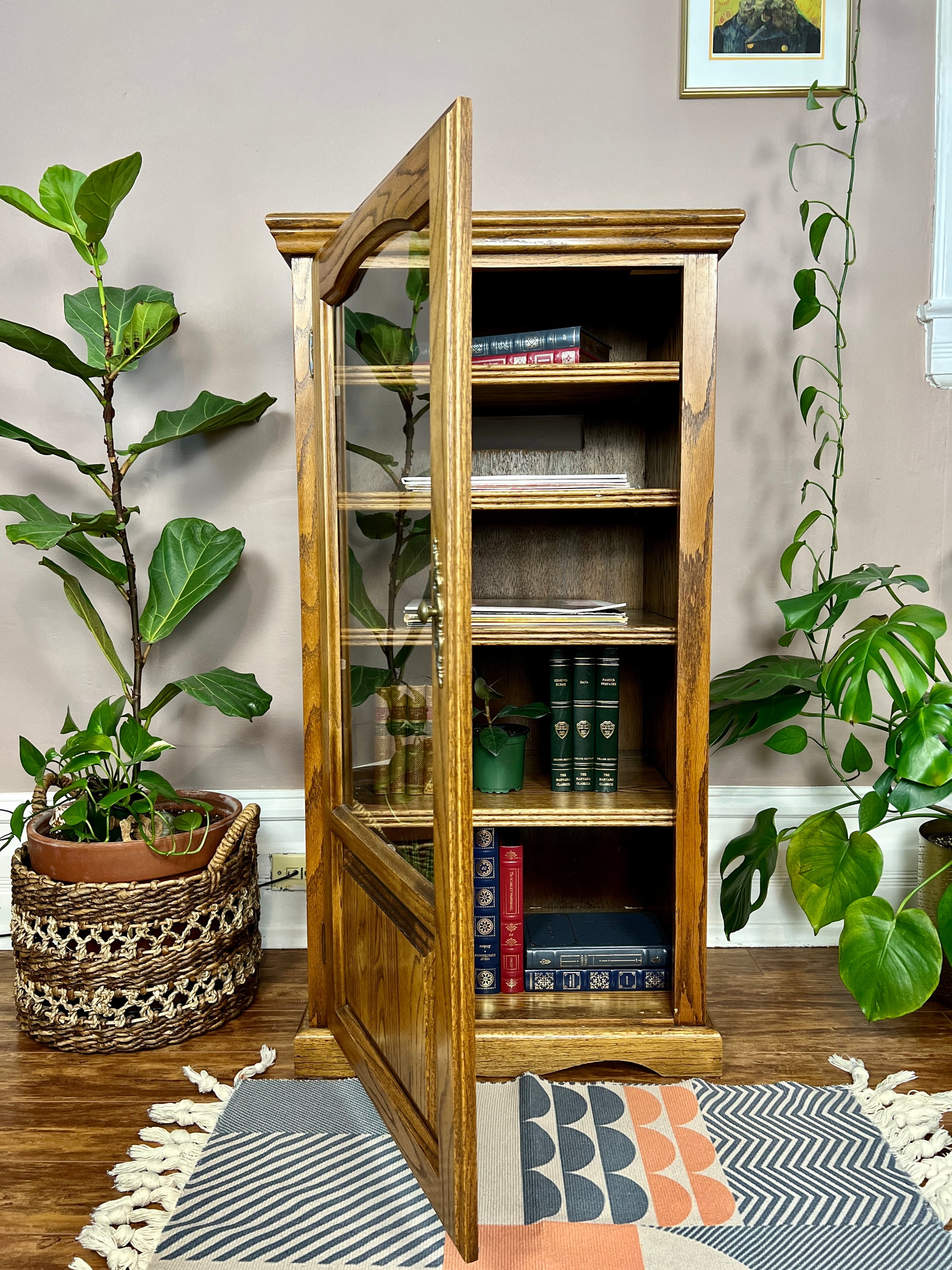 This is a vintage english oak record cabinet with 5 shelves and a glass door.