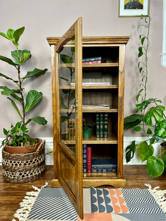 This is a vintage english oak record cabinet with 5 shelves and a glass door.