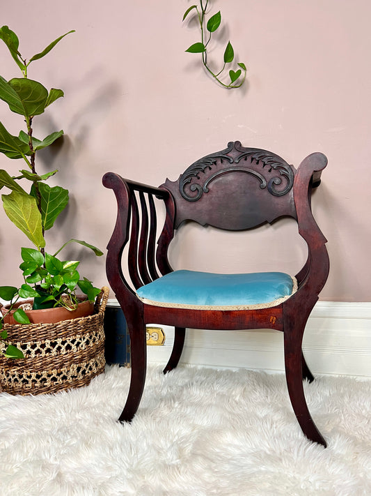 This a antique bentwood armchair with blue velvet seat cushion.