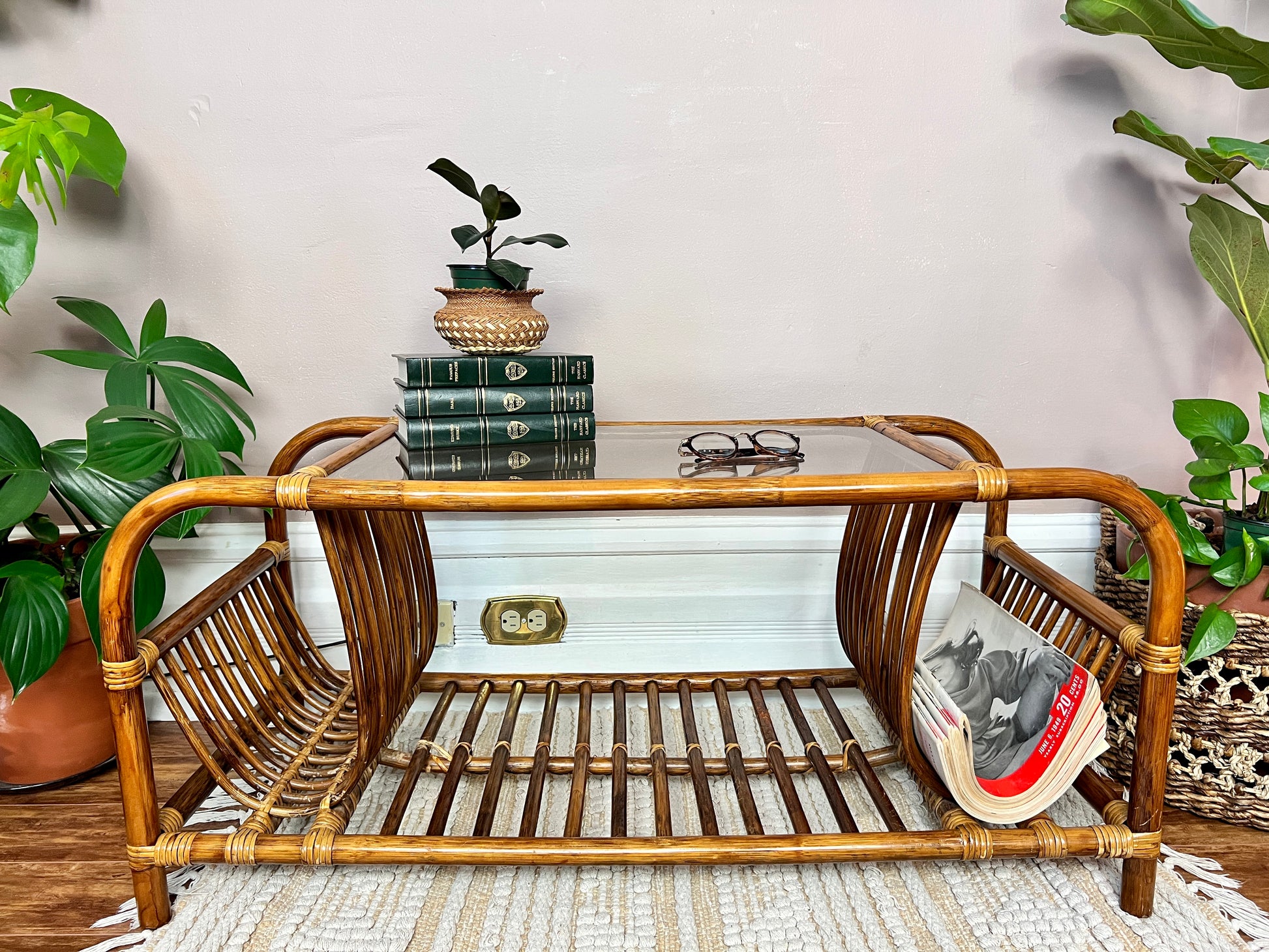 This is a unique rattan coffee table with glass top and curved magazine/record holders on each side.
