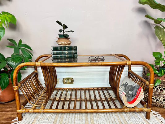 This is a unique rattan coffee table with glass top and curved magazine/record holders on each side.