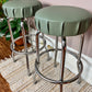 These are vintage bar stools with sage green vinyl tops that swivel and have chrome frames.