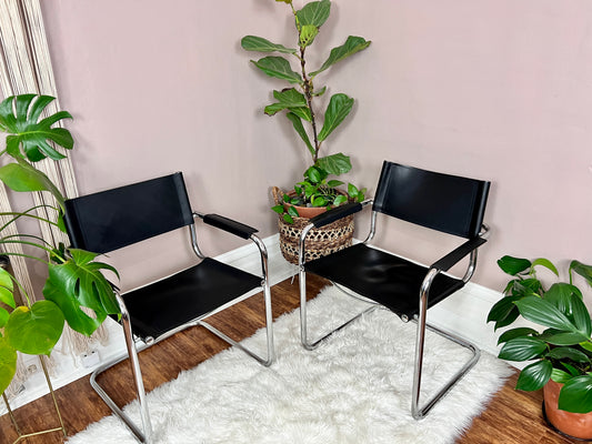 These are mart stam s34 chairs made in italy in the 1980s. They have a silver metal cantilever frame and black leather upholstery.